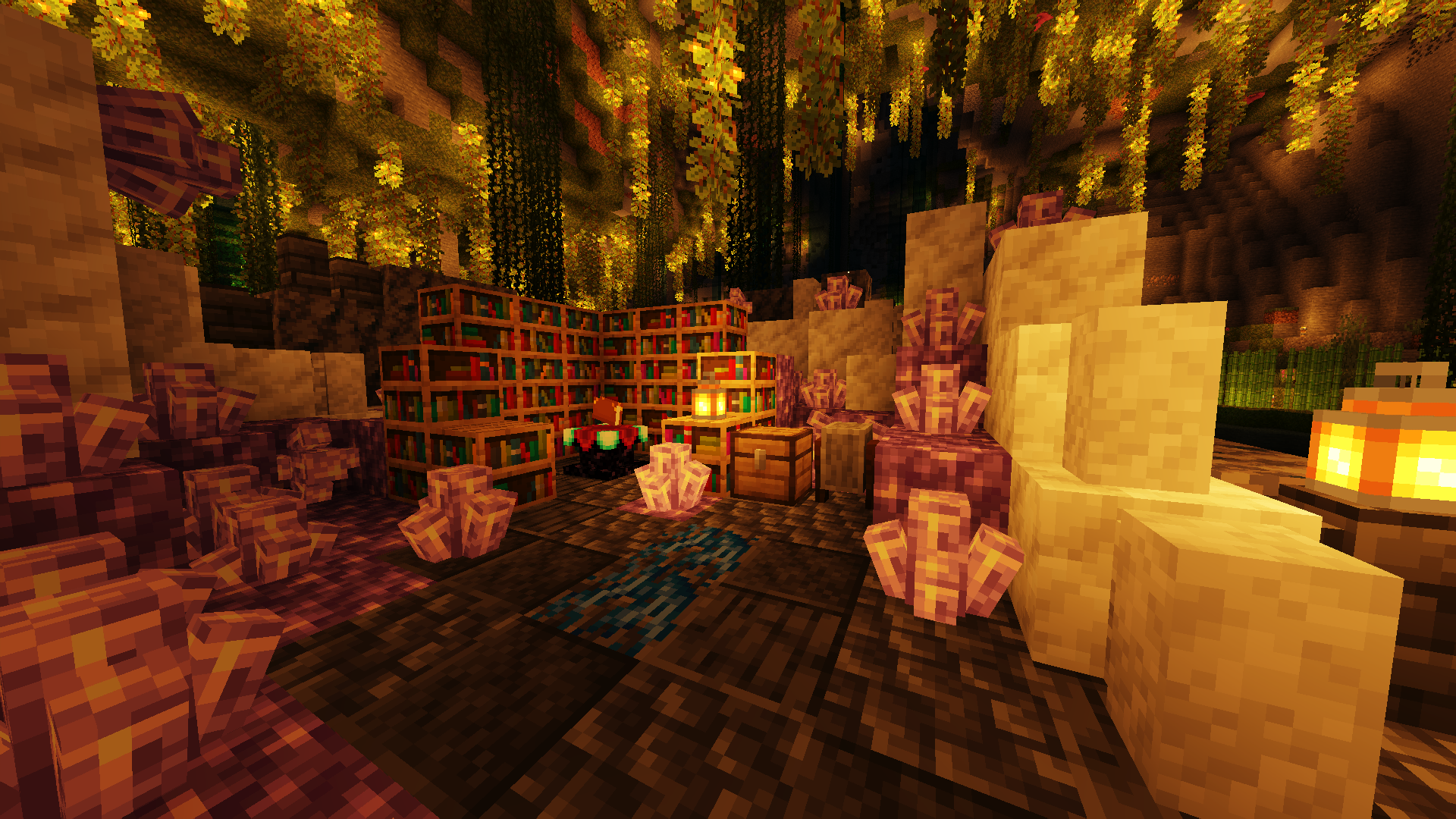 A screenshot of the game Minecraft. The screenshot shows an enchanting station situated in a chunk of a huge amethyst geode. The black outer shell and white inner layer of the geode have been formed into a platform and wall, with chunks of amethyst remaining. On the same platform are a chest and grindstone. The platform is floating on water inside a cave, everything bathed in warm light from nearby lanterns and glow berries growing from the ceiling.